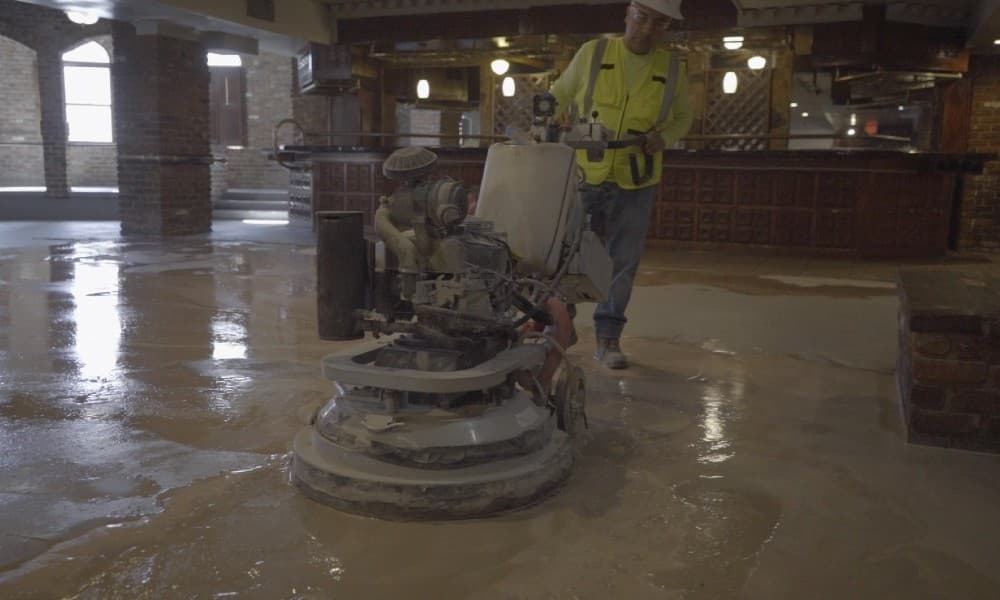 A Concreate worker wet-grinding concrete with a walk-behind grinder