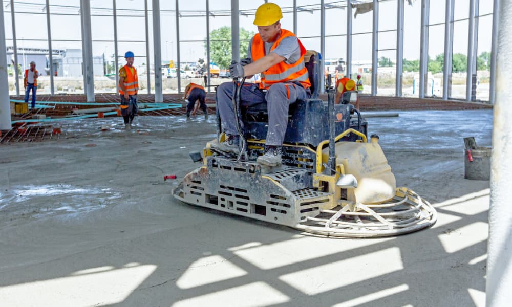 A concrete contractor using a polishing concrete machine to smooth out the surface.